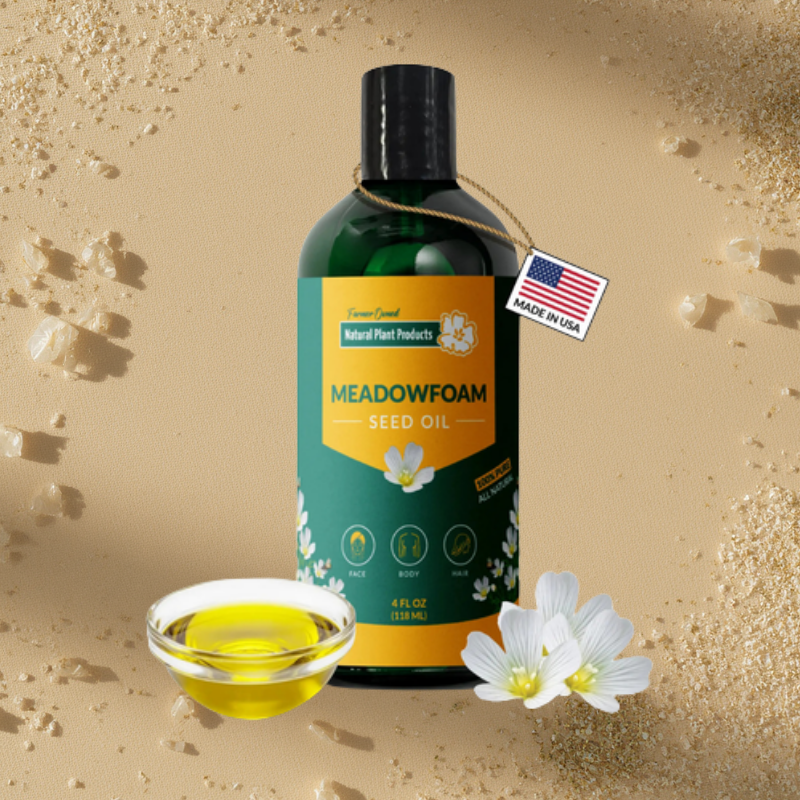 Pure Meadowfoam Seed Oil in green glass bottle with yellow label, Made in USA, natural botanical hair and skin moisturizer from Oregon, surrounded by oil in glass bowl and white flowers on sandy background