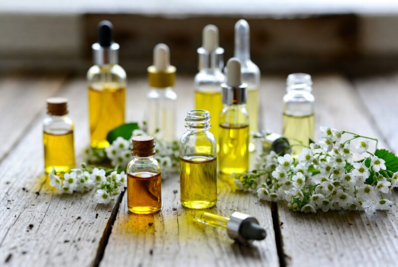 Natural botanical seed oils in glass bottles on rustic wooden table with fresh meadowfoam flowers, Oregon-grown skincare ingredients for natural moisturizers and formulation