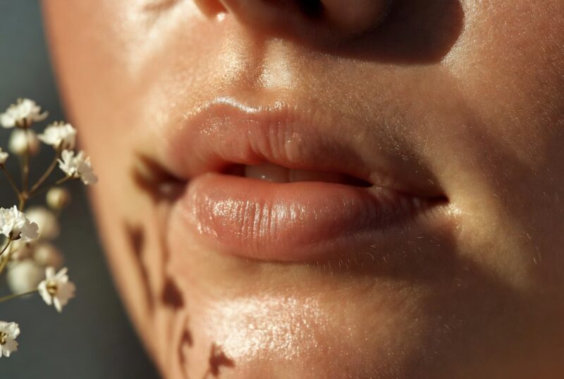 Close-up of soft, smooth, naturally hydrated pink lips with healthy shine from botanical lip oil, showing results of natural ingredients for dry chapped lipsImage 2 (Meadowfoam field)