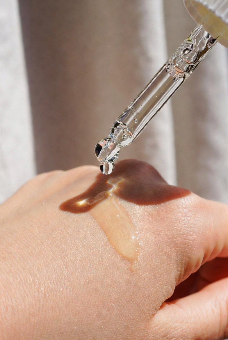 Lightweight clear Daikon Seed Extract oil dropper releasing a silky drop onto clean hand skin, demonstrating fast-absorbing natural moisturizer texture for face and body skincare