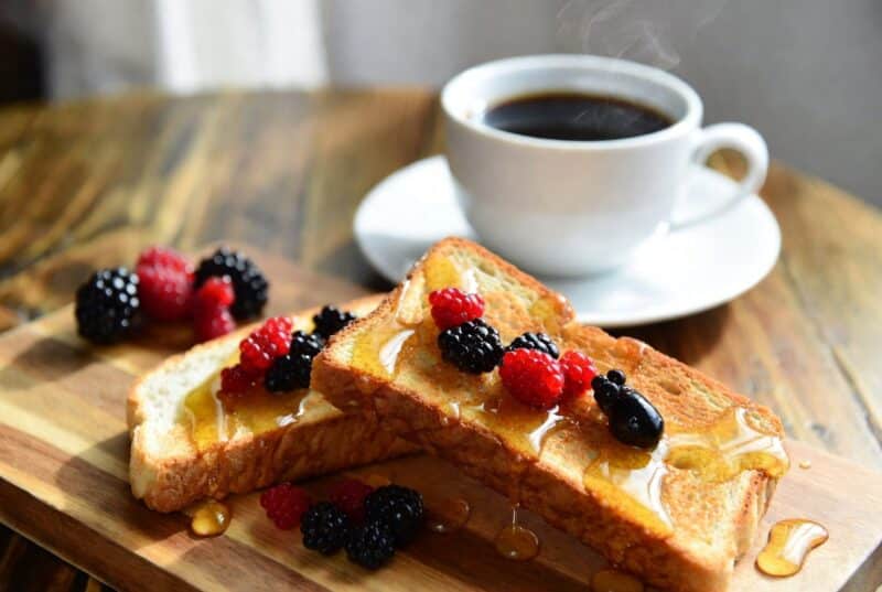Delicious slices of toast drizzled with sweet meadowfoam honey and topped with fresh berries next to coffee, perfect Oregon gourmet breakfast idea with vanilla honey