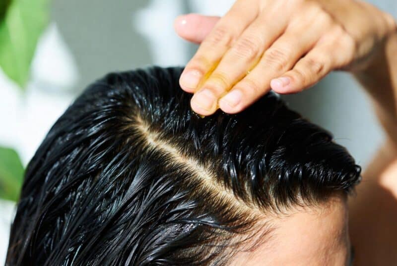 Close-up of hands massaging natural Abyssinian oil into scalp for healthy hair, lightweight botanical scalp treatment, natural hair care routine